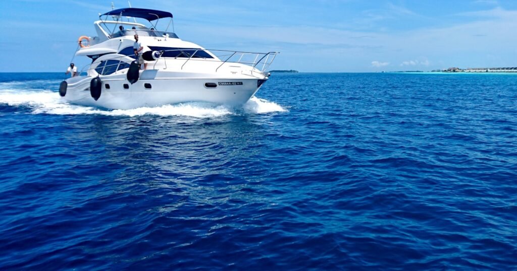 A white and blue sailing catamaran glides across calm turquoise Caribbean waters under a clear blue sky
