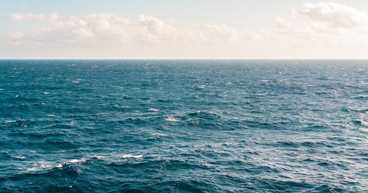 A sailing vessel moves through bright turquoise Caribbean sea water under a clear blue sky