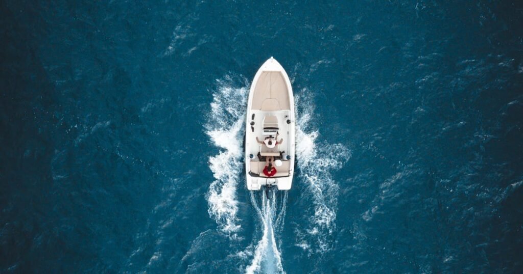 A sailing vessel moves through bright turquoise Caribbean sea water under a clear blue sky