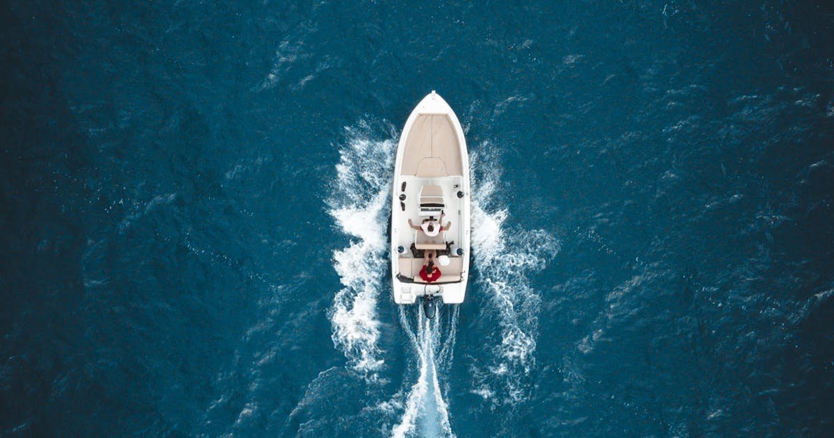 A sailing vessel moves through bright turquoise Caribbean sea water under a clear blue sky