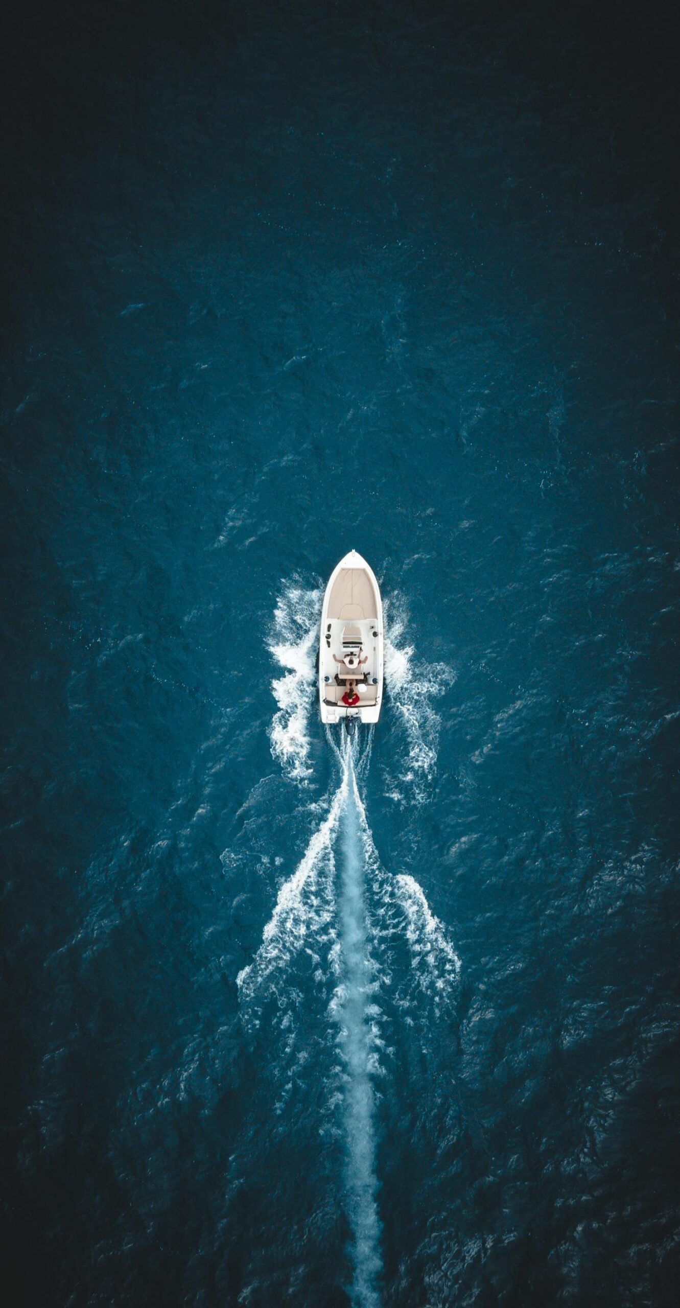 A sailing vessel moves through bright turquoise Caribbean sea water under a clear blue sky