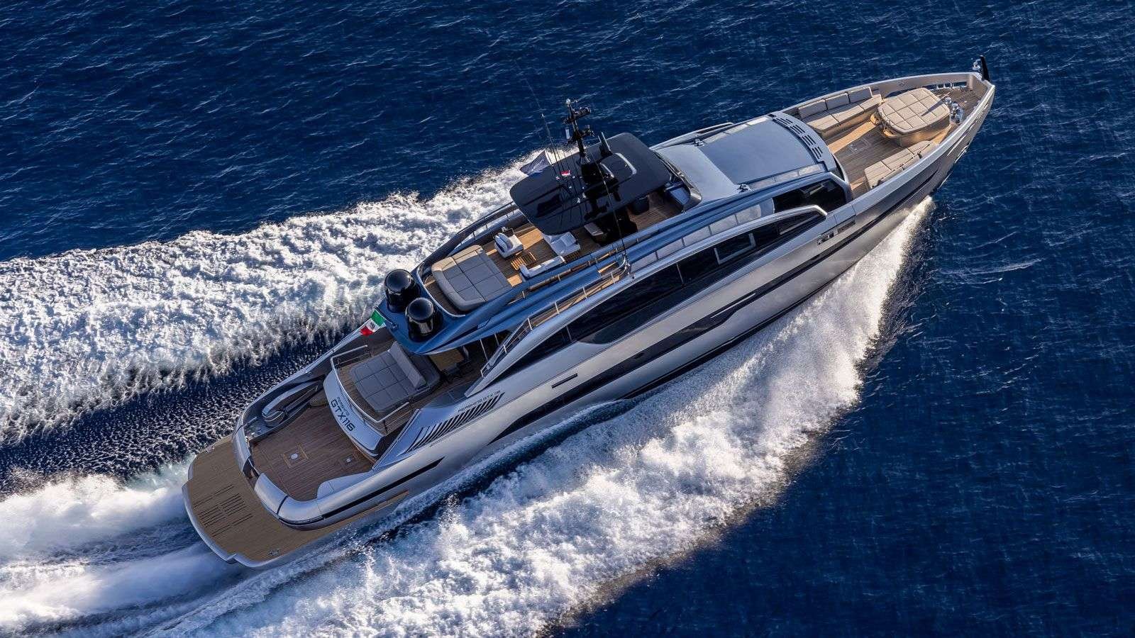 A sleek luxury motor yacht speeds through deep blue water, white wake trailing behind it.