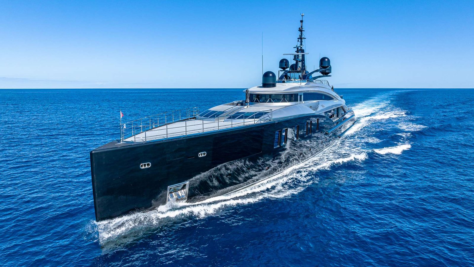 Luxurious black motor yacht cruising through the open blue sea on a sunny day