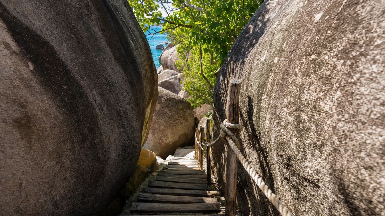 Wooden ladder and rope handrail leading hikers through a narrow squeeze between giant boulders on the Caves trail to Devil's Bay at The Baths Virgin Gorda