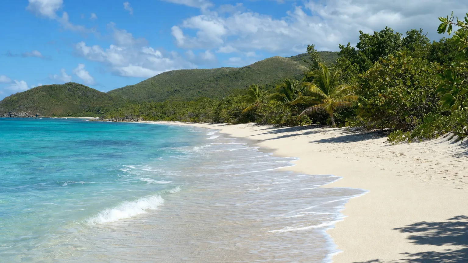 White sand beach with turquoise water and green hills on Mustique island in the Grenadines