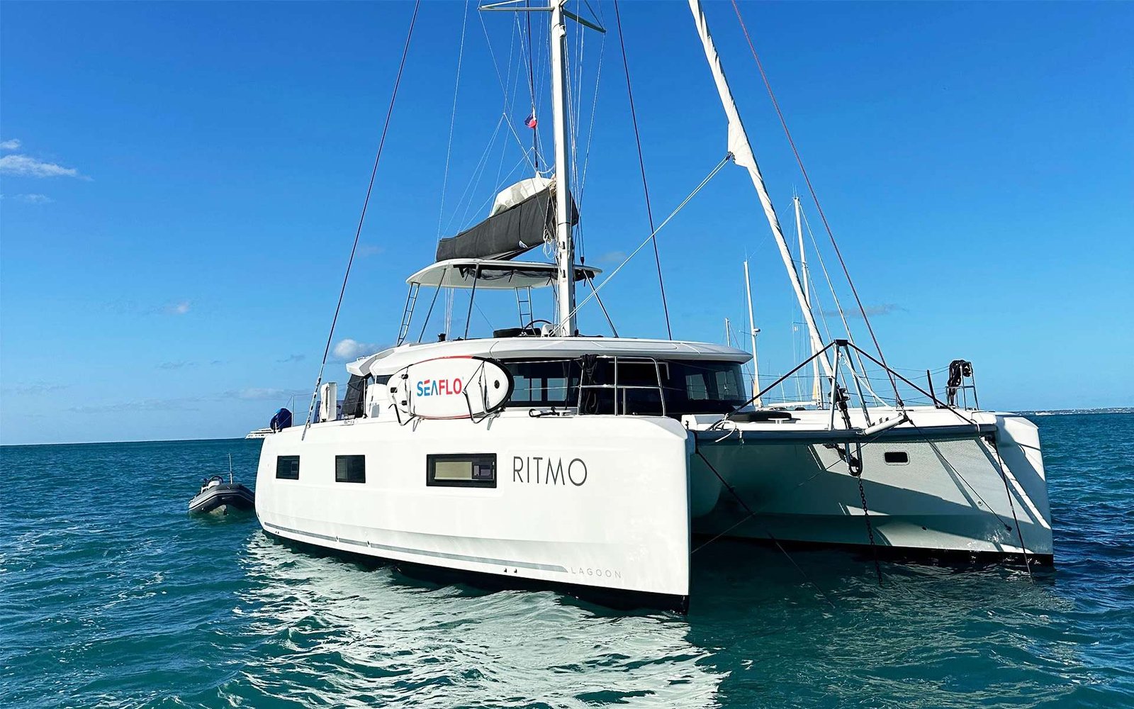 Catamaran named Ritmo on calm blue water with folded sails and clear sky above
