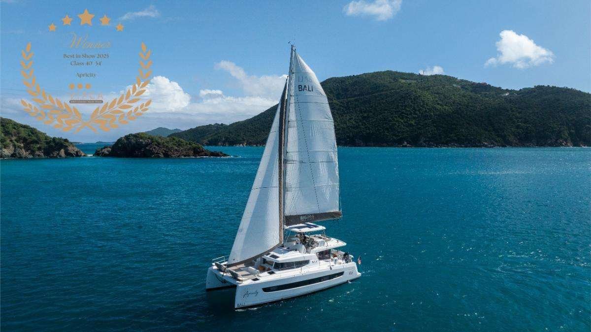 White sailing catamaran on bright blue water with green, forested hills in the background; a gold laurel award graphic over the left side of the image.