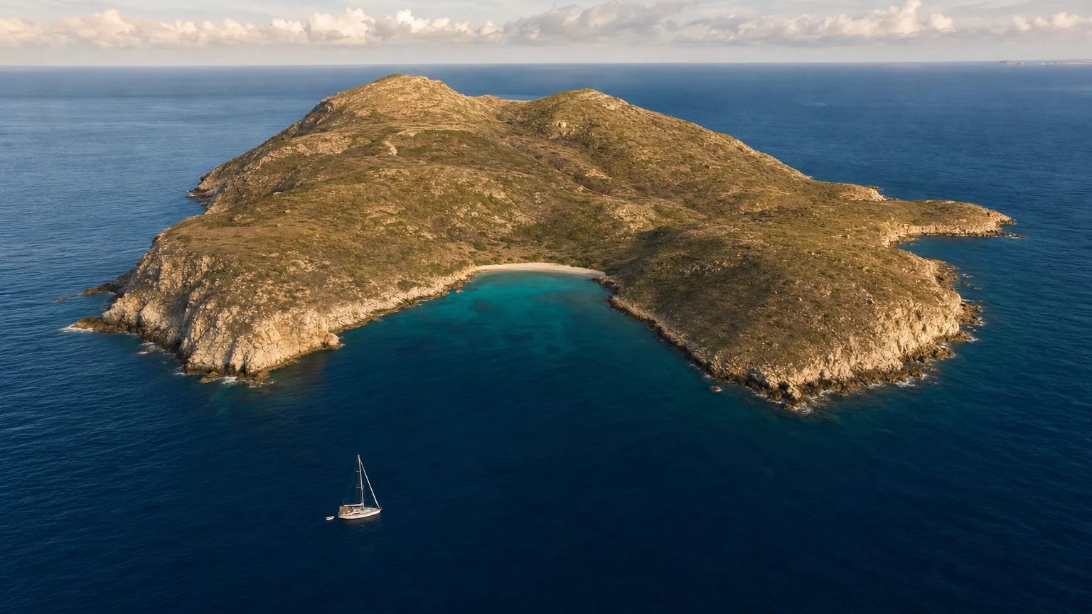 Uninhabited Ile Fourchue seen from the sea with its bay and sand beach in late afternoon light
