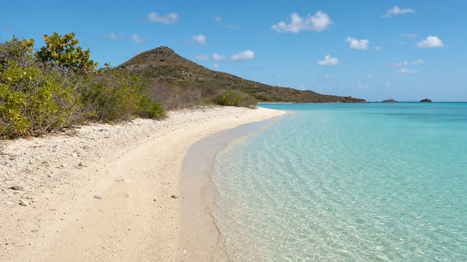 Sheltered west-facing beach and sandy spit on Pinel Island with calm clear shallow water