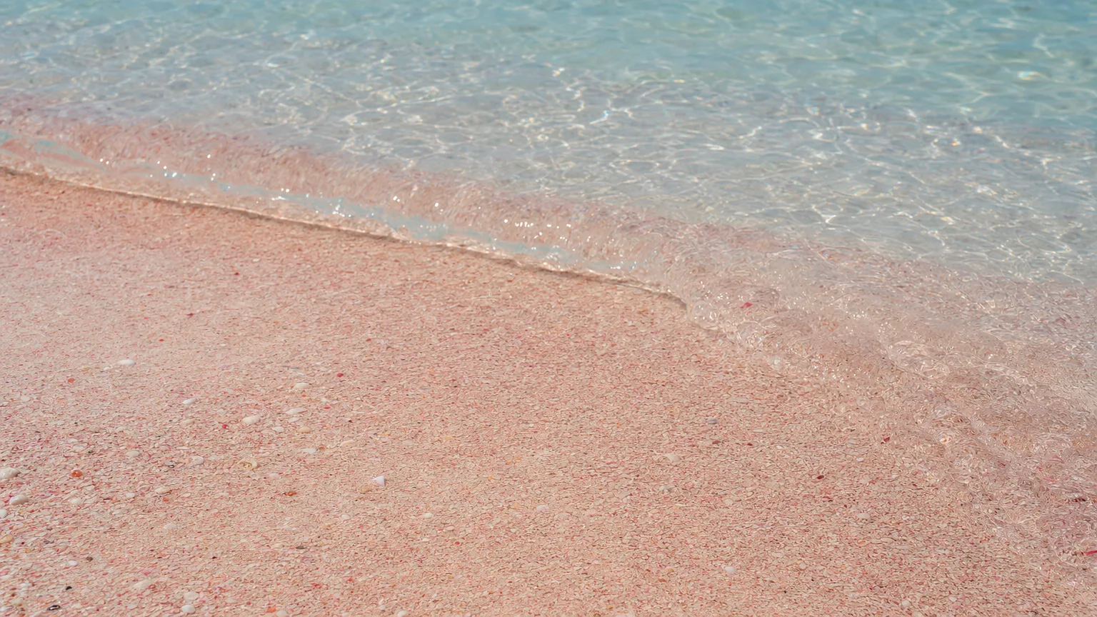 Close view of pale pink Harbour Island sand meeting clear turquoise water