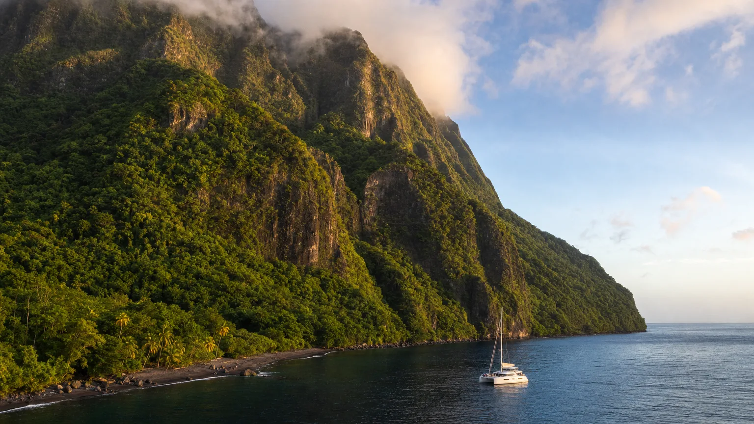 Steep volcanic Windward Islands peaks above a yacht anchored in a deep cove