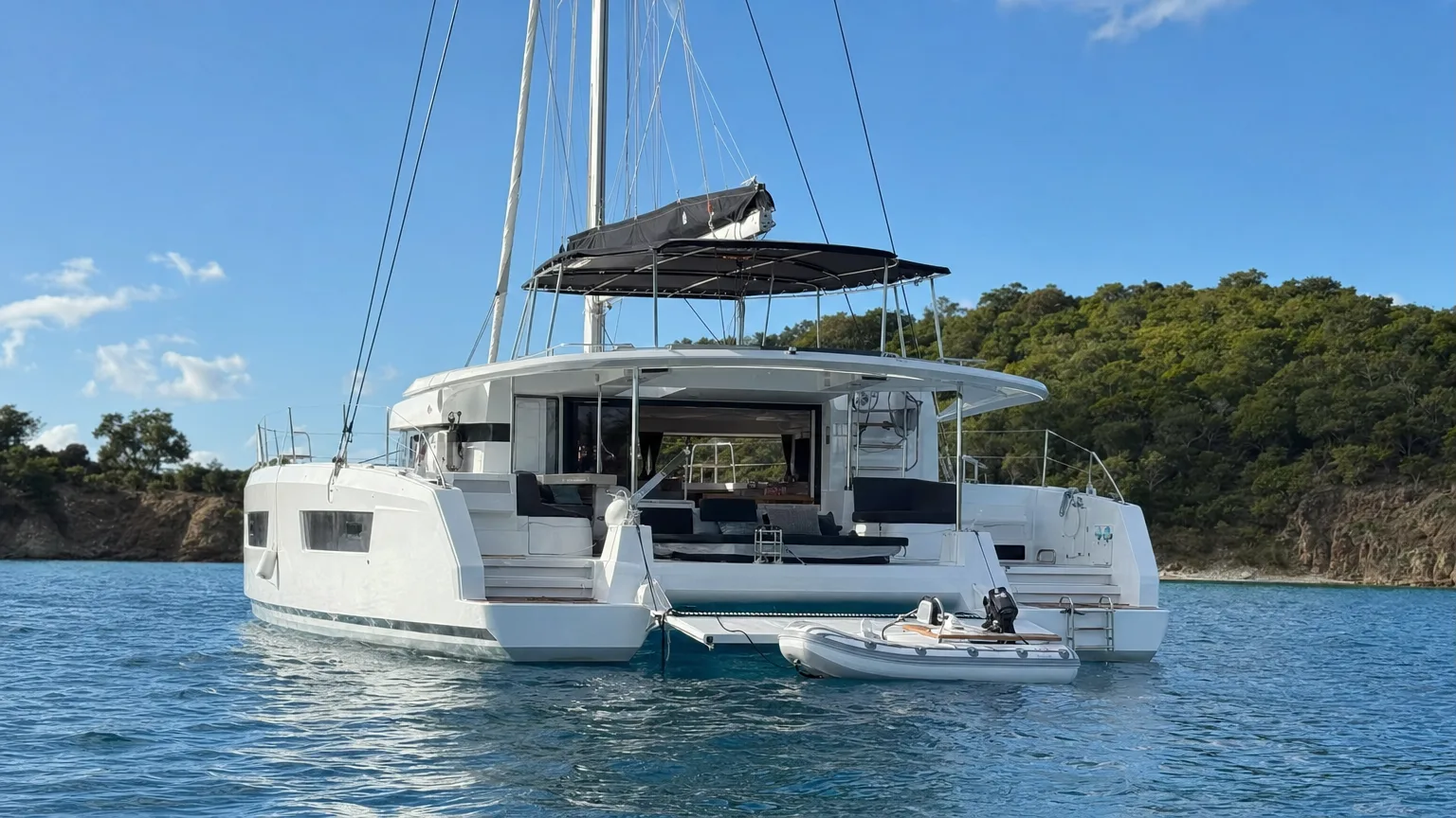 BVI catamaran charter with crew at anchor, swim platform down and dinghy astern