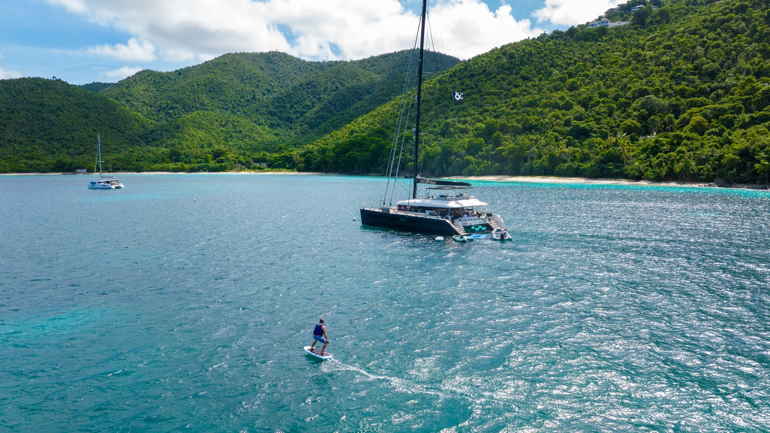 eFoil rider alongside MAHASATTVA, British Virgin Islands | Vital Charters eFoil rider beside the charter catamaran MAHASATTVA in the British Virgin Islands