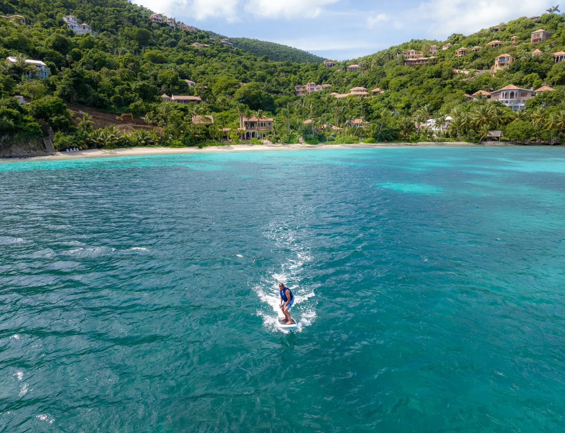 eFoil rider crossing a turquoise bay near MAHASATTVA