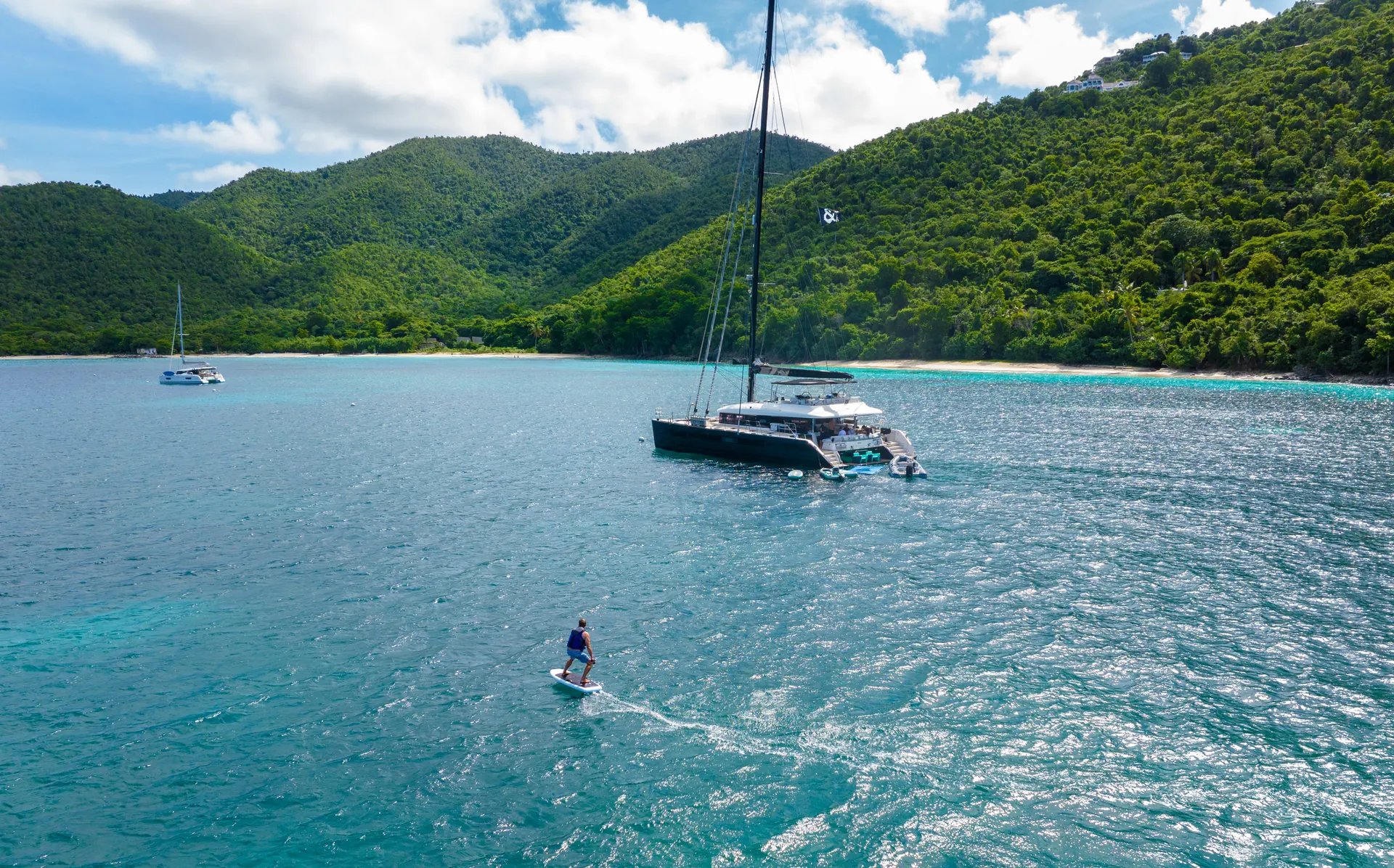 eFoil rider beside the catamaran MAHASATTVA