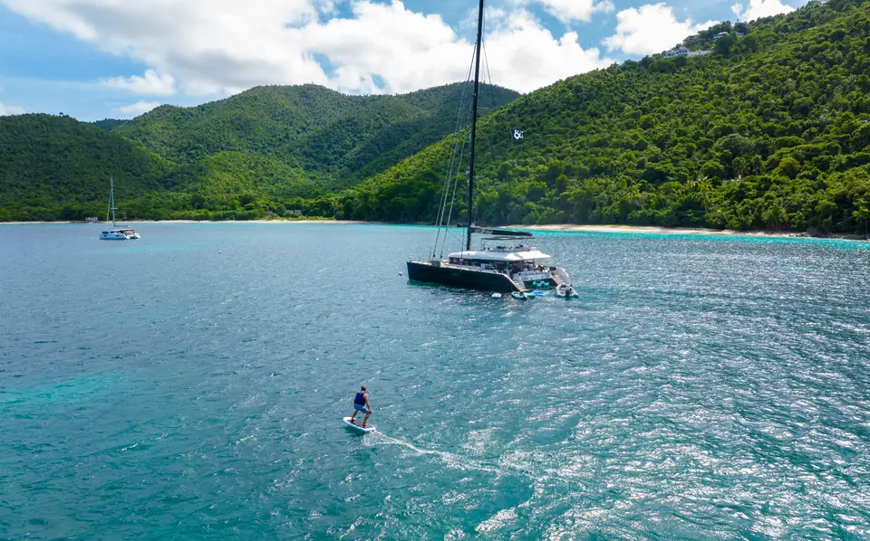 eFoil rider beside the catamaran MAHASATTVA