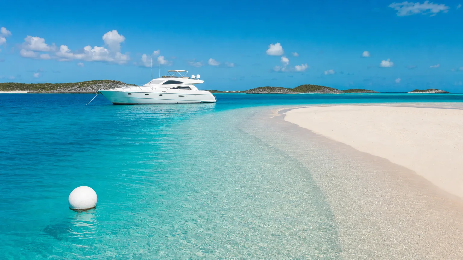 Motor yacht moored beside a sandbar in the Exuma Cays Land and Sea Park, where Bahamas charter taxes and park fees apply