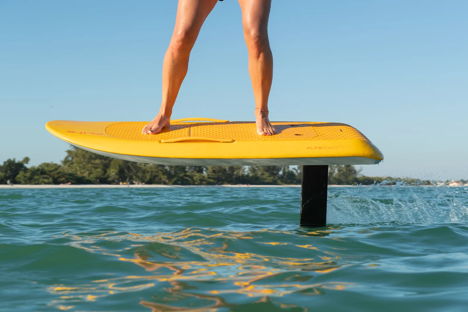 Close-up of a yellow Fliteboard eFoil riding just above the water on its mast