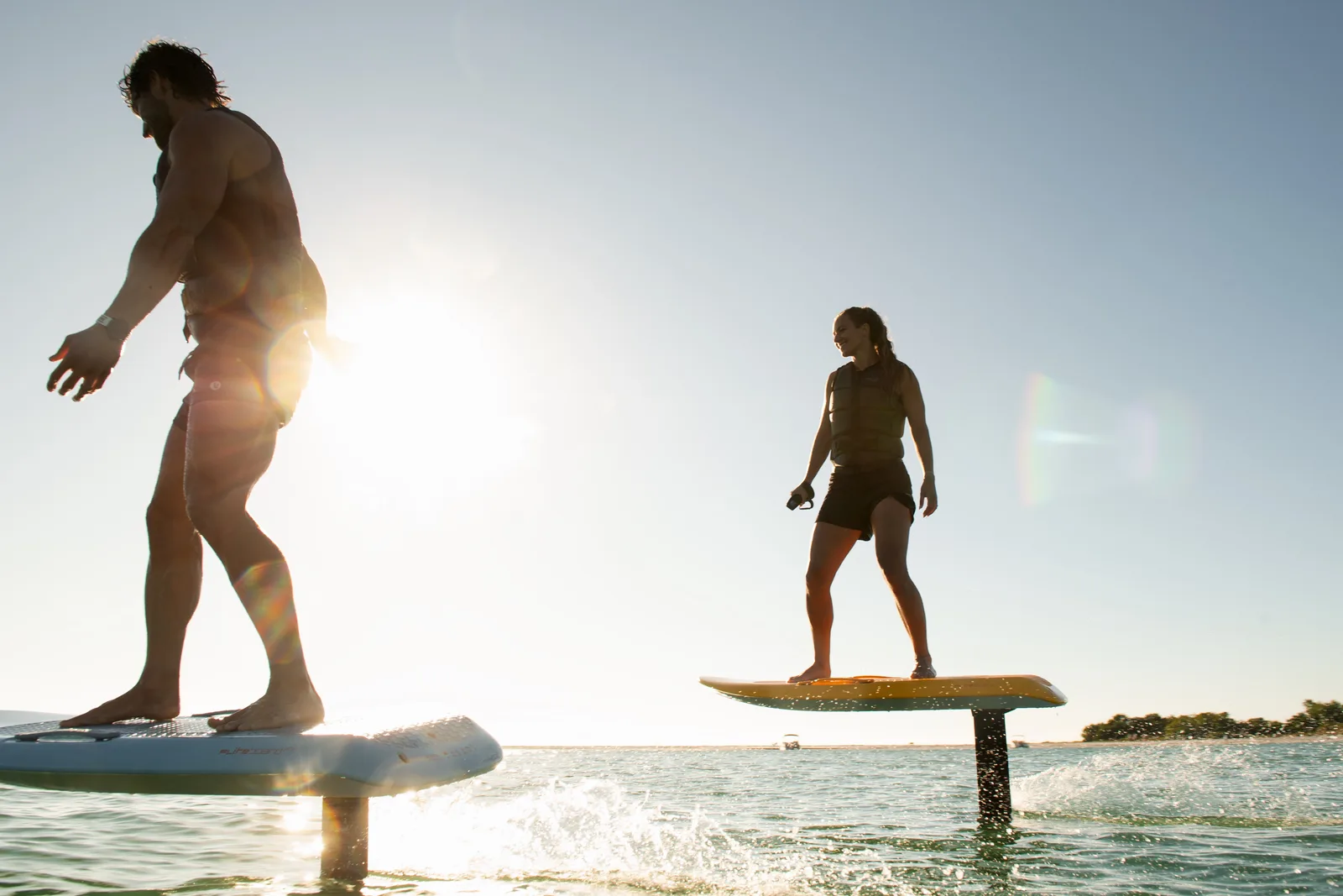 Two riders fly side by side on Fliteboard eFoils in bright sunshine