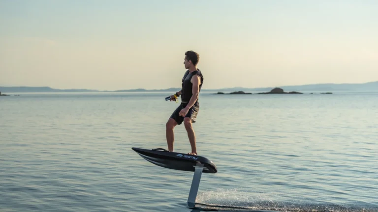 Rider flying above calm water on a SiFly eFoil at sunset, the board lifted clear on its hydrofoil
