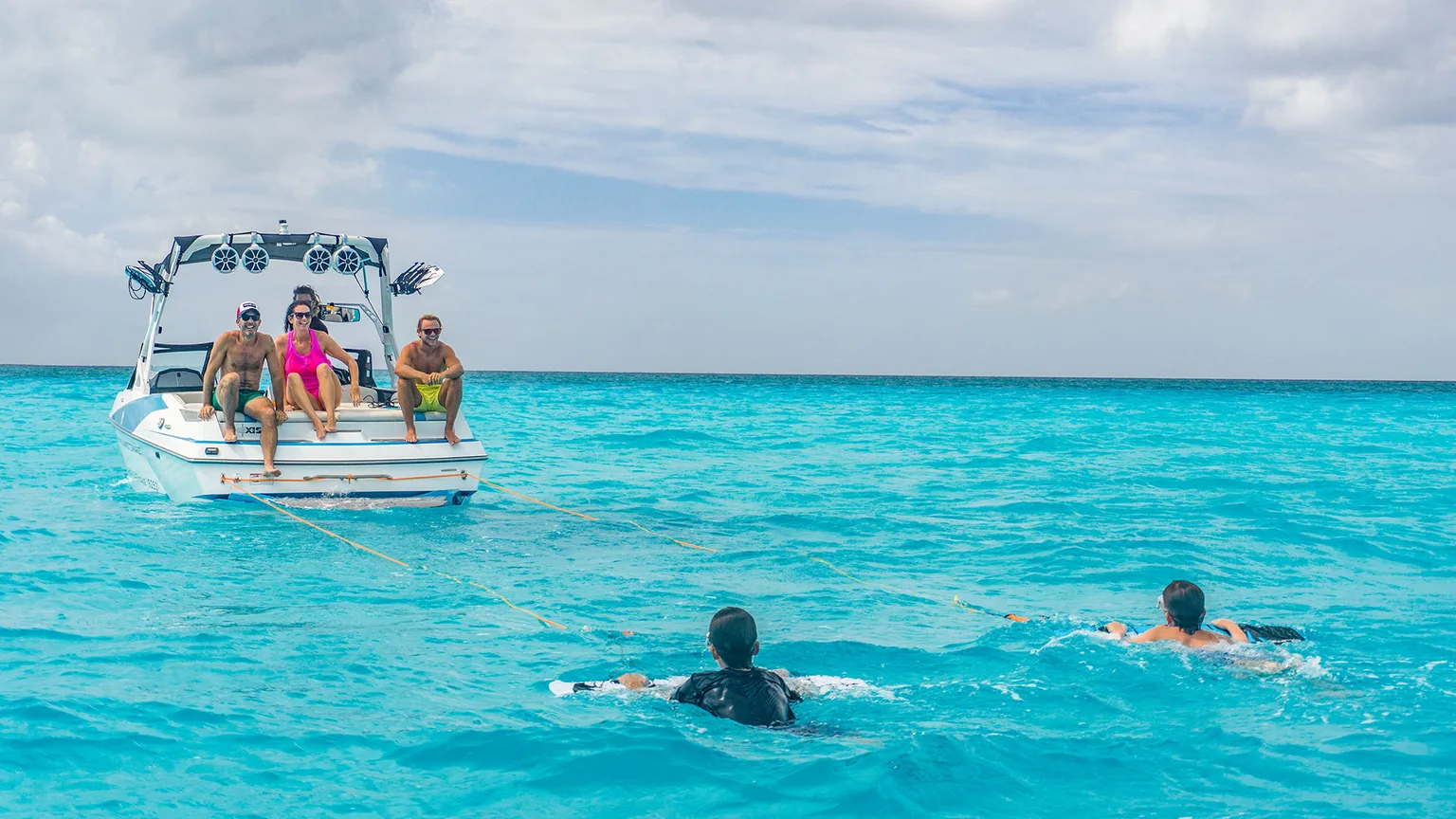 Guests watching from the boat while two Subwing riders ride behind it in turquoise water