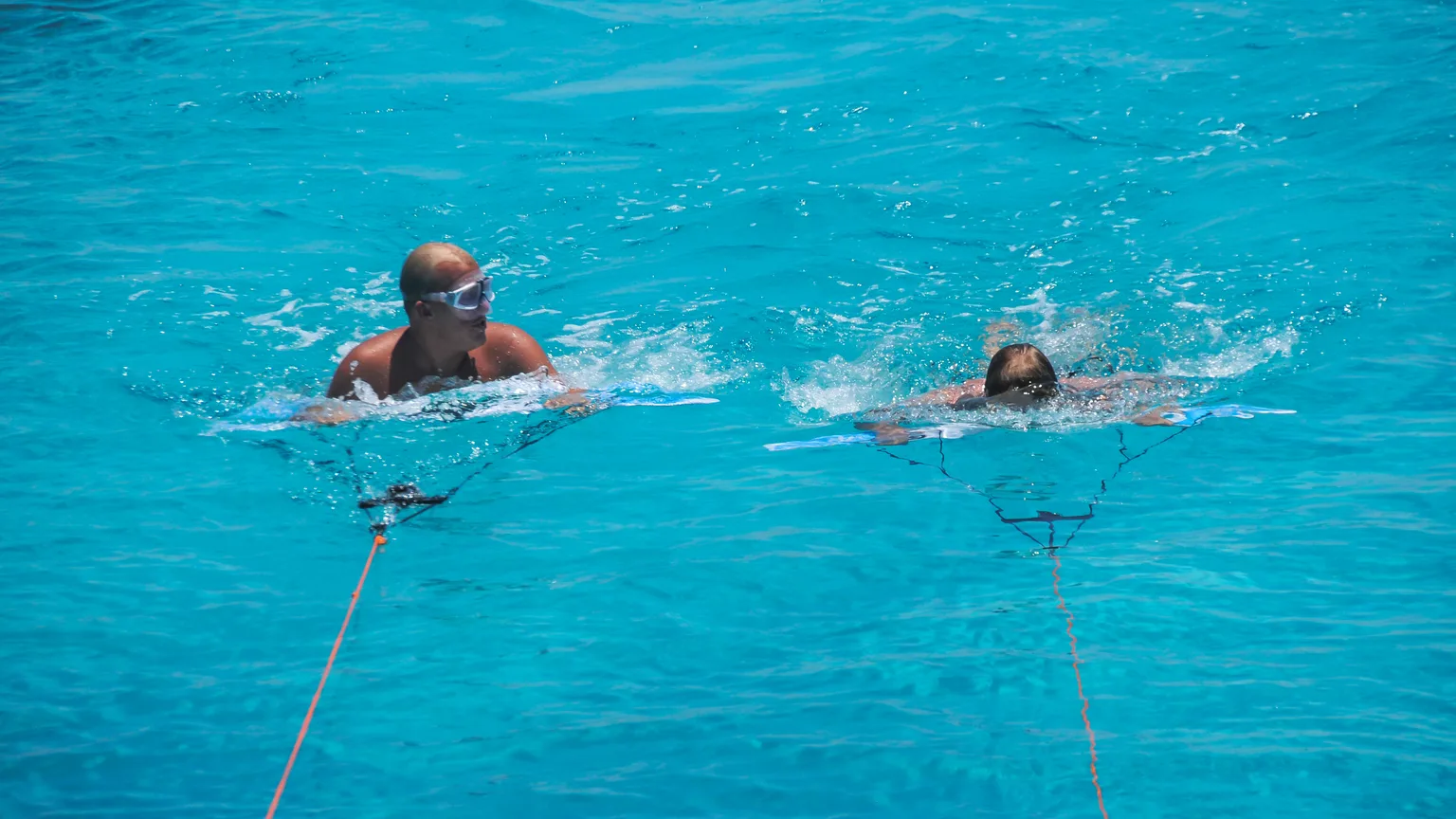 Two Subwing riders at the surface holding their wings before diving under