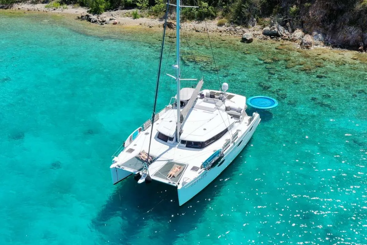 Odyssea is a beautiful 59' Fontaine Pajot chartering the BVI in the Caribbean.
Guests can relax in her spacious salon and enjoy watching all the delicious meals being prepared in the up galley. Dining on the aft deck offers alfresco dinging and relaxing on the sun-bed watching the sun set. Since we offer a wet bar, a cold beverage is never too far away; whether you are floating on the inflatable island, going for a sundowner cruise in our 15' tender or merely lying on the nets under the stars. A large sky lounge on salon roof where guests can enjoy sun bathing is a favourite spot to enjoy happy hour treats and some of the Captain's delicious cocktails all the while enjoying a 360° view and a soft sea breeze.
Come and join us in the British Virgin Islands onboard Odyssea!