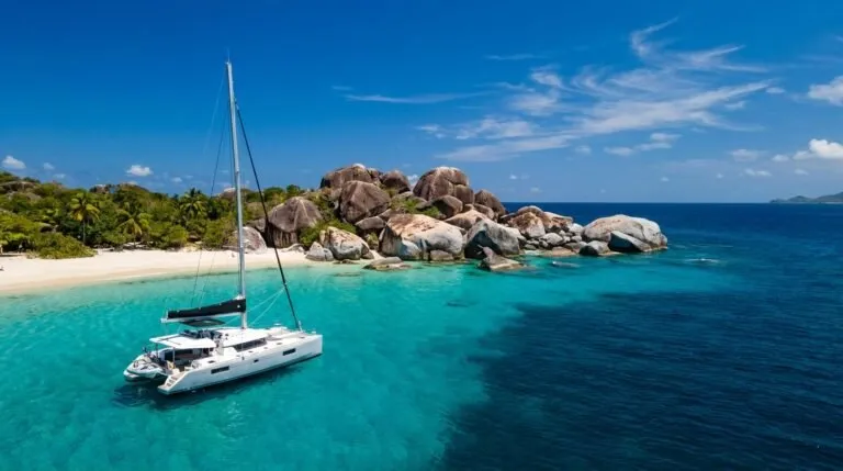 Luxury sailing catamaran anchored beside the iconic granite boulders of The Baths on Virgin Gorda in the British Virgin Islands